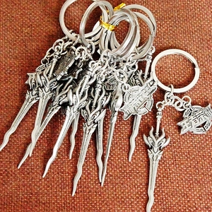 Detailed view of metal game weapon keychains with engraved logo on red fabric surface