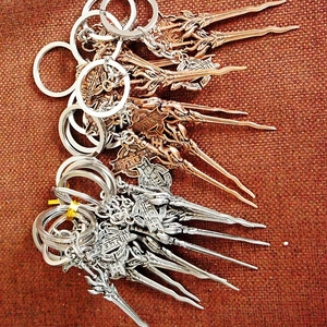 Zinc alloy game weapon keychains in silver and bronze finish on textured background