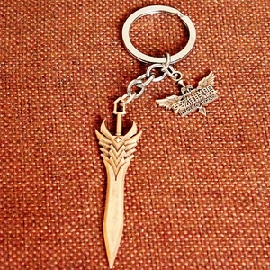 Detail view of a bronze sword keychain and League of Legends emblem on fabric