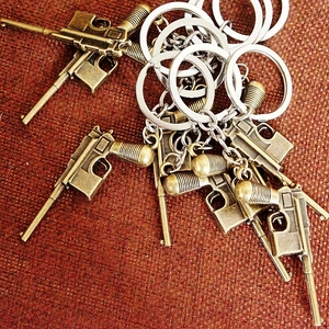 Detail of vintage bronze pistol-shaped metal keychains on a woven texture background