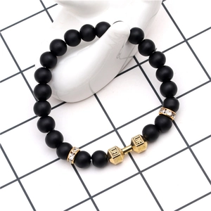 Bracciale fitness in pietra lavica 8mm con manubrio dorato su una mano in ceramica bianca