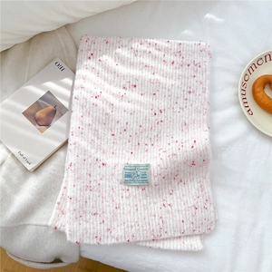 Close-up of pink and white chunky knit scarf with vertical stripes and brand label
