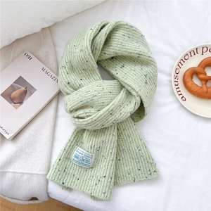 Detail shot of green chunky knit scarf with rib texture and branding label