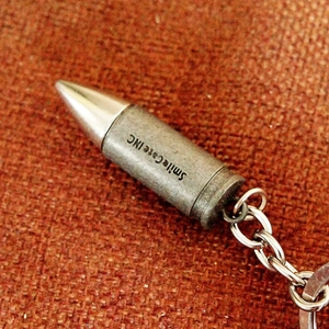 Macro shot of silver and bronze bullet shaped metal keychain on rustic fabric