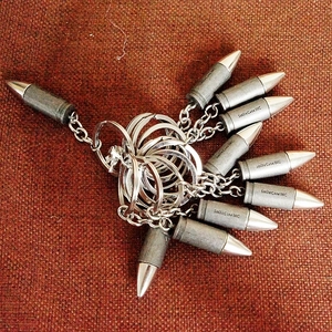 Detailed view of silver metal keychain with multiple bullet-shaped charms and engravings