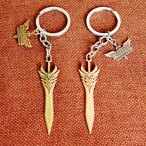 Detail of League of Legends gold and bronze metal pendants on woven texture background