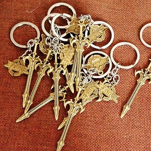 Sword-shaped metal keychains with game character relief on red fabric background