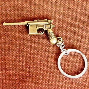 Close-up of bronze metal miniature pistol keychain on a brown textured background