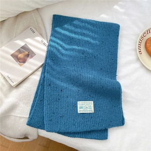 Close-up of blue knit scarf texture with woven label on a cozy minimalist background