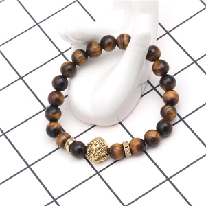 Macro detail of brown tiger eye bead bracelet with golden lion head on hand model