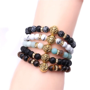 Close-up of beaded bracelets featuring golden lion heads, tiger eye, and turquoise stones