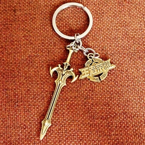 Close-up of bronze-finish metal sword keychain with inscribed round gaming pendant