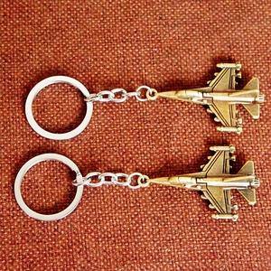 Top view of two vintage bronze airplane model keychains on a textured background