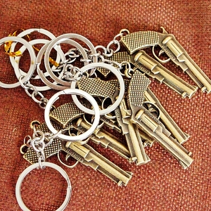 Detail of multiple bronze replica handgun keychains with metal ring and engraved logo