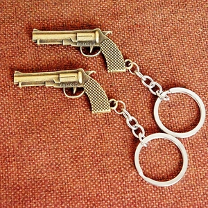 Detail of bronze-finished mini revolver metal keychains with textured grip and engraving