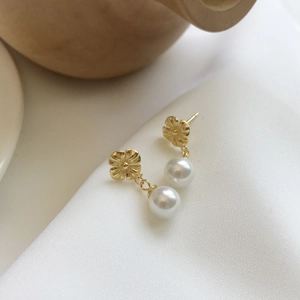 Elegant 925 sterling silver flower earrings with white pearls on a white satin background
