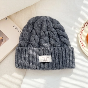 Detailed close-up of 100% wool knit beanie with woven brand label and cable stitch texture