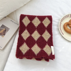 Dettaglio ravvicinato della sciarpa in maglia spessa con motivo a rombi bordeaux e beige