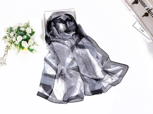 Detail of thin chiffon scarf featuring black and white gradient leaf pattern on wood tray