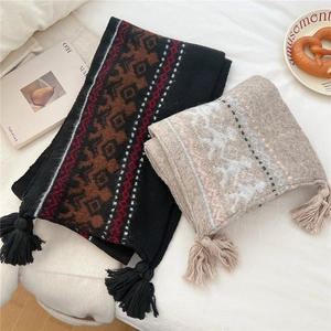 Close-up of ethnic knit scarves with thick tassels in brown and grey displayed on white linen