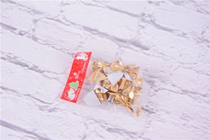 Detailed view of twelve gold decorative Christmas bows in clear plastic packaging