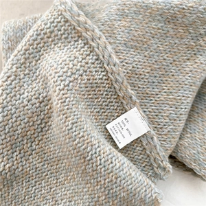 Macro shot showing the 100% wool material label and soft knit texture of this scarf