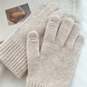 Detail of beige knitted winter gloves with touch-screen fingertips and ribbed windproof cuffs