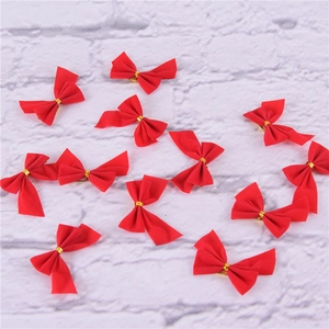 Set of mini red flocked Christmas bows with gold ties on white textured background