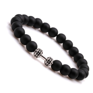 Macro shot of black matte stone beads and dumbbell charm with micro-pave crystals
