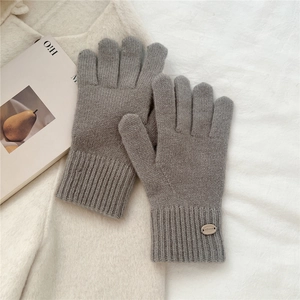 Close-up of grey knit gloves with elastic ribbed cuffs and decorative brand label