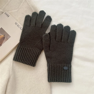 Close-up of dark grey knitted gloves with warm ribbed cuffs on a soft white fabric