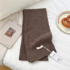 Detail shot of brown 100% wool scarf showing high-quality knit texture and care label