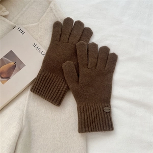 Close-up of dark brown knitted gloves with elongated ribbed cuffs on soft wool background