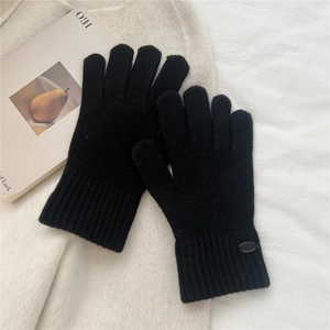 Detail of black knitted gloves with textured fabric and ribbed cuffs on soft background