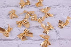 Close-up of small golden decorative bows with metallic texture for gift wrapping