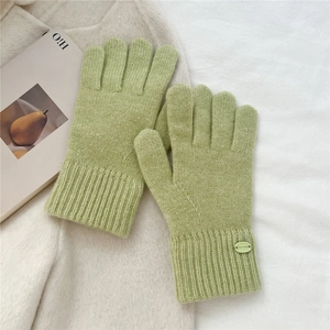 Close-up of matcha green knitted gloves with ribbed cuffs and refined brand label detail