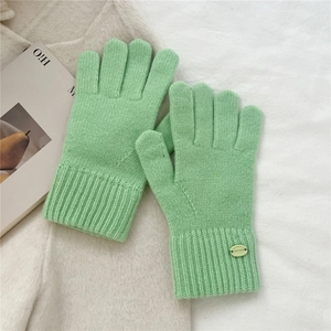 Detailed view of light green knit gloves featuring ribbed cuffs and decorative brand button