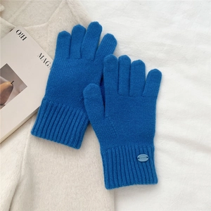 Close-up of bright blue knitted winter gloves with ribbed cuffs and metallic logo detail
