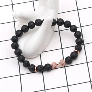 Detailed macro view of black volcanic lava beads and a rose gold dumbbell charm with zircons