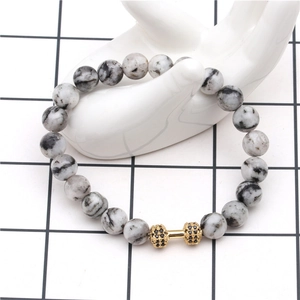Macro shot of lava stone dumbbell bracelet on a ceramic hand display stand