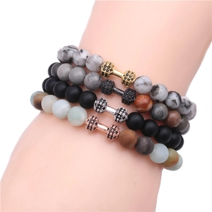Close-up of four matte stone dumbbell bracelets in black, marble, and teal colors