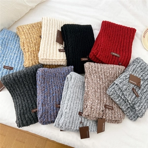 Flat lay showing various colorful knitted scarves with thick ribbed texture in warm tones