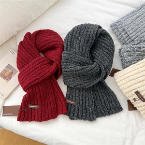 Close-up of thick rib-knitted scarves in multiple colors with leather logo patches