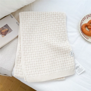 Close-up of thick cream white wool knit scarf showing luxury basketweave texture