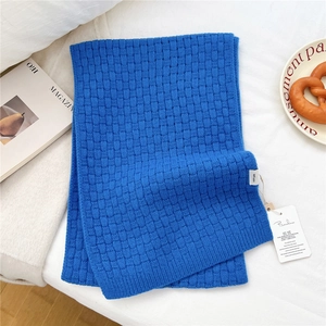 Macro detail of royal blue knitted wool scarf with 100% wool label and textured weave