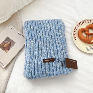 Detail of blue and white knitted scarf with premium leather tag on a soft textured background
