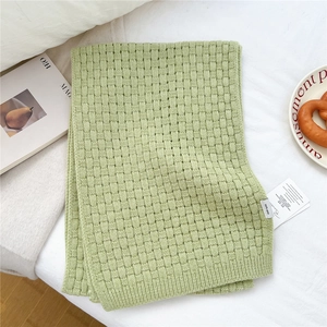Detailed texture of thick woven wool scarf in light green with warm knitted grid pattern