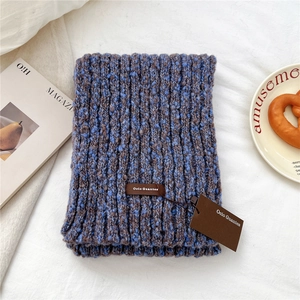 Detail of blue and brown mixed knit scarf featuring a premium leather brand logo label