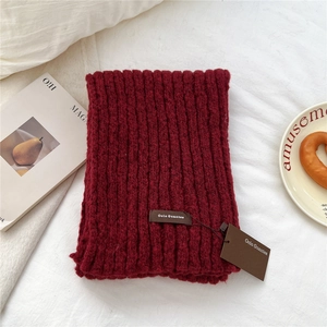Detailed macro view of burgundy knitted scarf texture with premium brand logo tag
