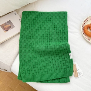 Detailed macro view of green wool knitted scarf texture with 100% wool material label